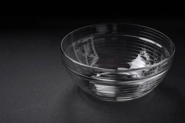 暗いコンクリートの背景に自宅で調理するための台所用品の要素として透明なガラスボウル — ストック写真