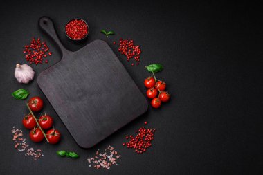 Koyu beton zeminde domates, tuz, baharat ve otlar pişirmek için gerekli malzemeler.