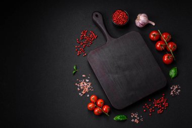 Koyu beton zeminde domates, tuz, baharat ve otlar pişirmek için gerekli malzemeler.