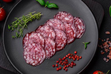 Lezzetli füme sosis, domuz pastırması, tuz, baharat ve ağaç kesme tahtasında dilimlenmiş otlar.