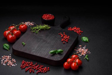 Koyu beton zeminde domates, tuz, baharat ve otlar pişirmek için gerekli malzemeler.