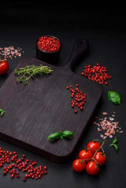 Koyu beton zeminde domates, tuz, baharat ve otlar pişirmek için gerekli malzemeler.