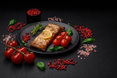 Tuzlu, baharatlı ve otlu lezzetli bir balık dilimi seramik bir tabakta koyu beton arka planda.