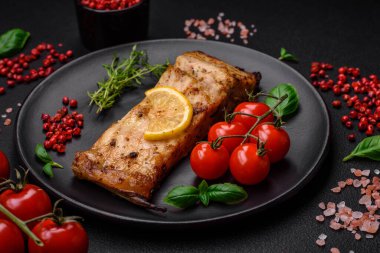 Tuzlu, baharatlı ve otlu lezzetli bir balık dilimi seramik bir tabakta koyu beton arka planda.