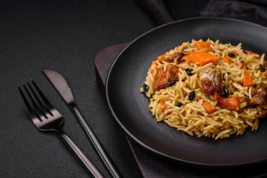 Lezzetli taze pilav, pirinç, havuç, et, soğan, baharat ve böğürtlen ile koyu beton arka planda seramik bir tabakta.