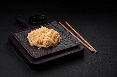 Koyu beton arka planda seramik bir tabakta tuz ve baharat içeren lezzetli kurutulmuş mürekkep balığı.