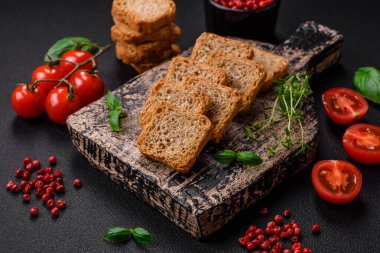 Lezzetli tuzlu dikdörtgen buğday ekmeği. Koyu beton arka planda tuz ve baharatlarla.