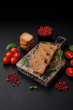 Lezzetli tuzlu dikdörtgen buğday ekmeği. Koyu beton arka planda tuz ve baharatlarla.
