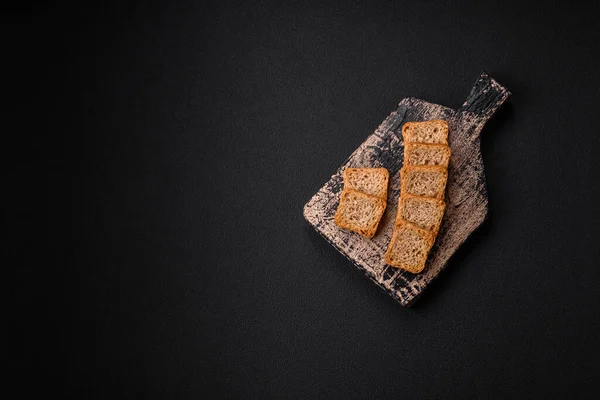 stock image Delicious salted rectangular wheat croutons with salt and spices on a dark concrete background