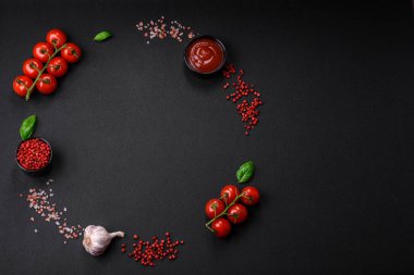 Koyu beton zeminde domates, tuz, baharat ve otlar pişirmek için gerekli malzemeler.
