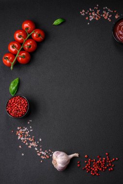 Koyu beton zeminde domates, tuz, baharat ve otlar pişirmek için gerekli malzemeler.