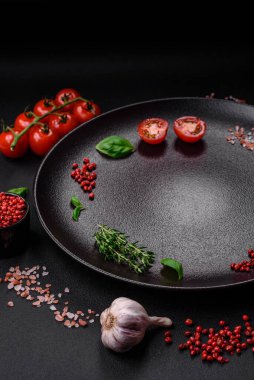 Koyu beton zeminde domates, tuz, baharat ve otlar pişirmek için gerekli malzemeler.