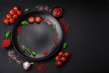 Koyu beton zeminde domates, tuz, baharat ve otlar pişirmek için gerekli malzemeler.