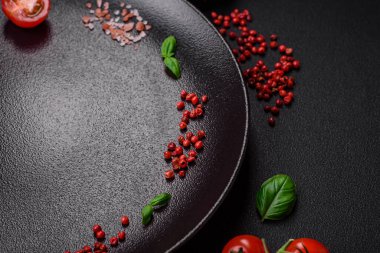 Koyu beton zeminde domates, tuz, baharat ve otlar pişirmek için gerekli malzemeler.