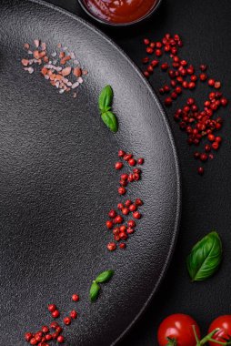 Koyu beton zeminde domates, tuz, baharat ve otlar pişirmek için gerekli malzemeler.