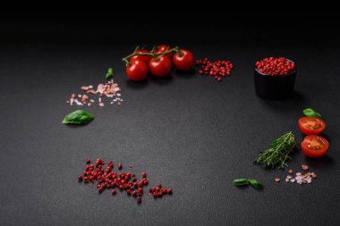 Koyu beton zeminde domates, tuz, baharat ve otlar pişirmek için gerekli malzemeler.