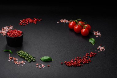 Koyu beton zeminde domates, tuz, baharat ve otlar pişirmek için gerekli malzemeler.