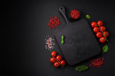 Koyu beton zeminde domates, tuz, baharat ve otlar pişirmek için gerekli malzemeler.