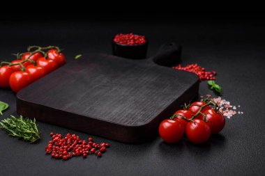 Koyu beton zeminde domates, tuz, baharat ve otlar pişirmek için gerekli malzemeler.