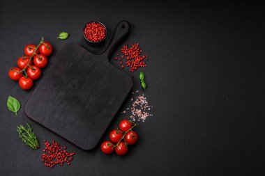 Koyu beton zeminde domates, tuz, baharat ve otlar pişirmek için gerekli malzemeler.