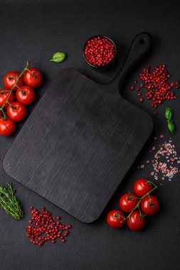 Koyu beton zeminde domates, tuz, baharat ve otlar pişirmek için gerekli malzemeler.