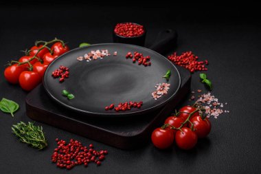 Koyu beton zeminde domates, tuz, baharat ve otlar pişirmek için gerekli malzemeler.