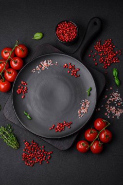 Koyu beton zeminde domates, tuz, baharat ve otlar pişirmek için gerekli malzemeler.