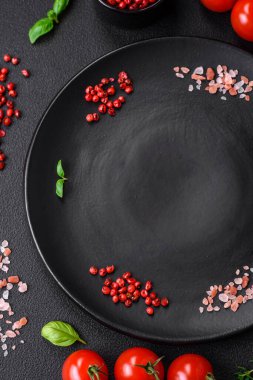 Koyu beton zeminde domates, tuz, baharat ve otlar pişirmek için gerekli malzemeler.