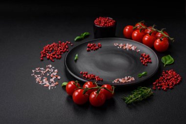 Koyu beton zeminde domates, tuz, baharat ve otlar pişirmek için gerekli malzemeler.