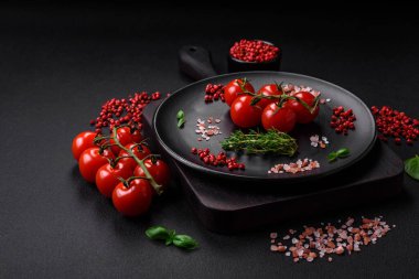 Koyu beton zeminde domates, tuz, baharat ve otlar pişirmek için gerekli malzemeler.