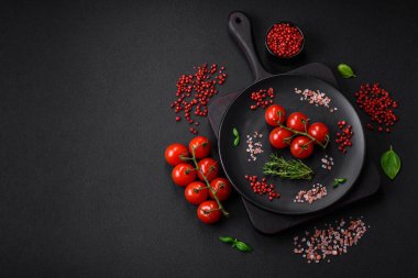 Koyu beton zeminde domates, tuz, baharat ve otlar pişirmek için gerekli malzemeler.