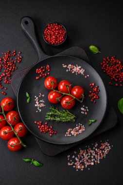 Koyu beton zeminde domates, tuz, baharat ve otlar pişirmek için gerekli malzemeler.