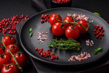 Koyu beton zeminde domates, tuz, baharat ve otlar pişirmek için gerekli malzemeler.