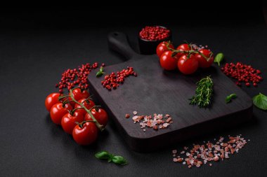 Koyu beton zeminde domates, tuz, baharat ve otlar pişirmek için gerekli malzemeler.