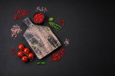 Koyu beton zeminde domates, tuz, baharat ve otlar pişirmek için gerekli malzemeler.