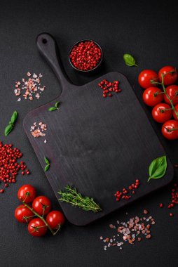 Koyu beton zeminde domates, tuz, baharat ve otlar pişirmek için gerekli malzemeler.