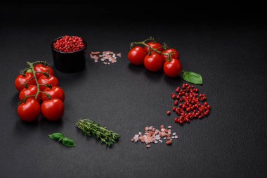Koyu beton zeminde domates, tuz, baharat ve otlar pişirmek için gerekli malzemeler.