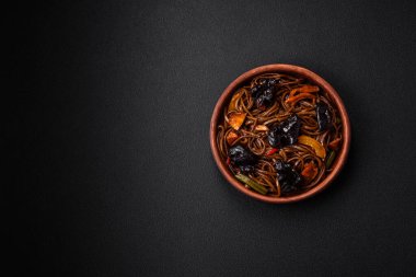 Lezzetli taze karabuğday eriştesi ya da mantarlı udon, biber ve diğer sebzeler, baharatlar ve otlar koyu beton arka planda.