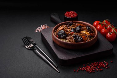 Lezzetli taze karabuğday eriştesi ya da mantarlı udon, biber ve diğer sebzeler, baharatlar ve otlar koyu beton arka planda.