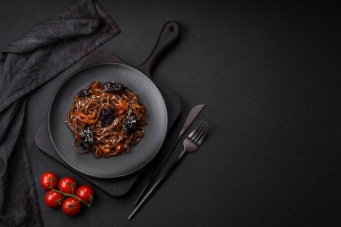 Lezzetli taze karabuğday eriştesi ya da mantarlı udon, biber ve diğer sebzeler, baharatlar ve otlar koyu beton arka planda.