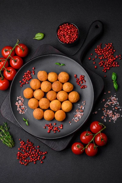 stock image Delicious fried potato balls with breaded mozzarella, salt, spices and herbs on a dark concrete background