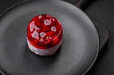 Lezzetli taze peynirli kek, böğürtlenli ve kırmızı renkli jöle, koyu beton arka planda.