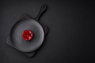 Lezzetli taze peynirli kek, böğürtlenli ve kırmızı renkli jöle, koyu beton arka planda.