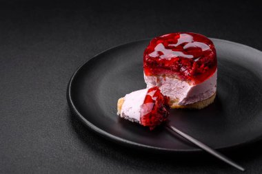 Lezzetli taze peynirli kek, böğürtlenli ve kırmızı renkli jöle, koyu beton arka planda.