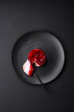 Lezzetli taze peynirli kek, böğürtlenli ve kırmızı renkli jöle, koyu beton arka planda.