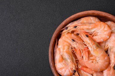 Lezzetli taze kaynamış kaplan karidesleri. Koyu beton bir zeminde seramik tabakta tuz ve baharatlarla.