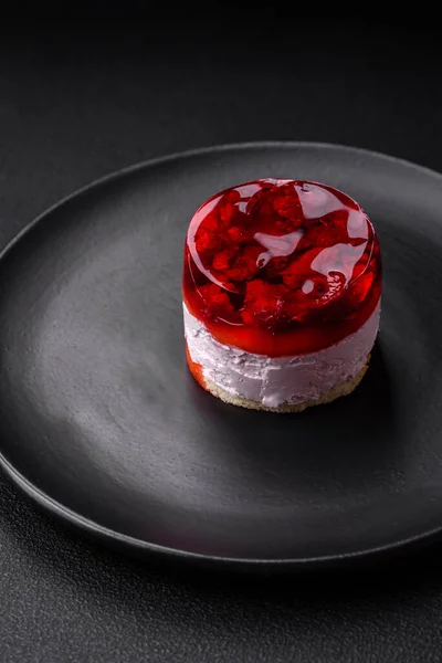 stock image Delicious fresh sweet cheesecake cake with berries and red color jelly on a dark concrete background