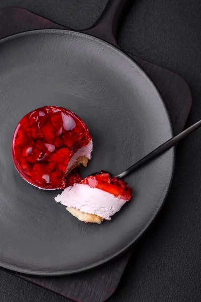 stock image Delicious fresh sweet cheesecake cake with berries and red color jelly on a dark concrete background