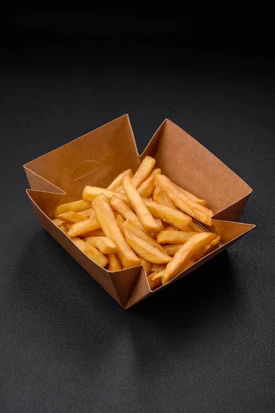 어두운 콘크리트 배경에 골판지 상자에 향신료를 맛있는 바삭바삭 감자튀김 — 스톡 사진