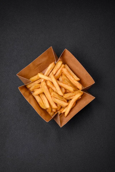 어두운 콘크리트 배경에 골판지 상자에 향신료를 맛있는 바삭바삭 감자튀김 — 스톡 사진